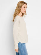 Beige long-sleeve top with subtle sparkle, shown on model.  Slightly curved hem.