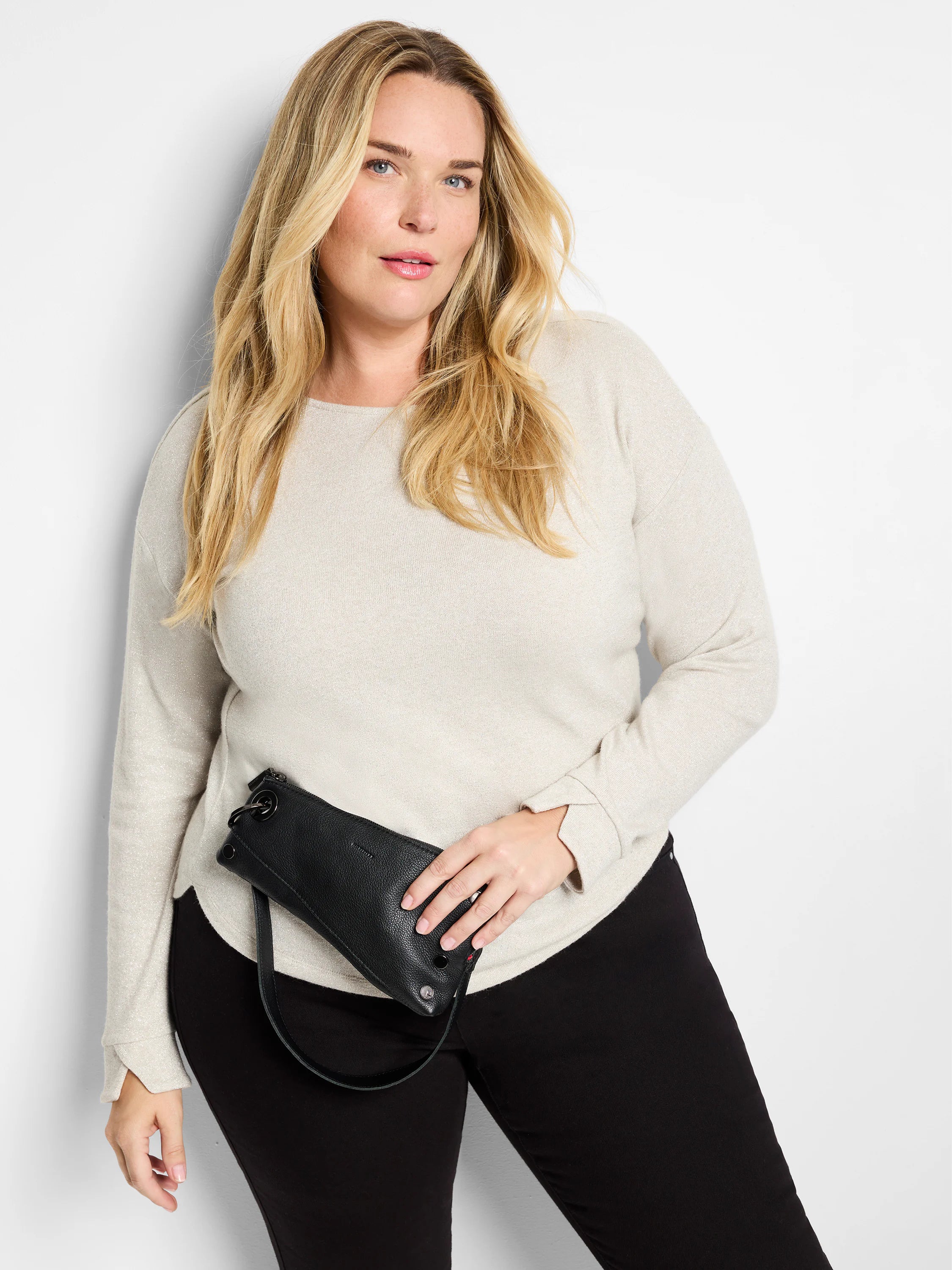 Beige sparkly long-sleeve top with subtle cuff detail. Model also wears black pants.