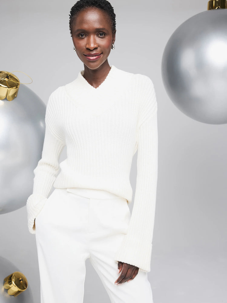 Off-white ribbed V-neck sweater.  Long sleeves with ribbed cuffs.  The sweater is shown on a model.