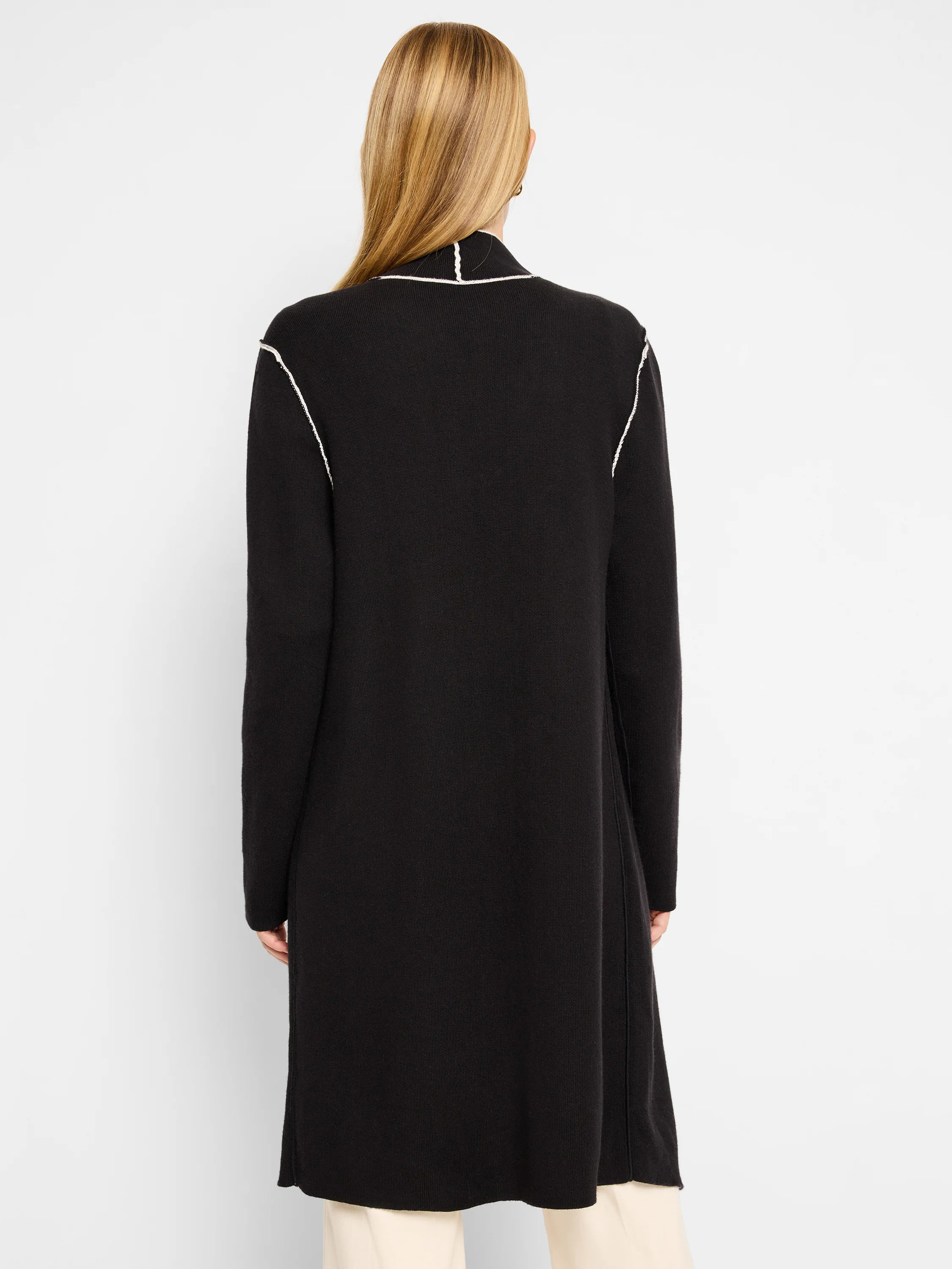 Black long jacket with white exposed stitching on the collar and shoulder seams.