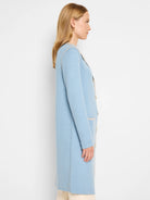 Knee-length light blue knit jacket with cream lapel, front buttons, and patch pockets.