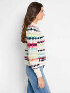 Off-white waffle-knit sweater with horizontal stripes in teal, pink, lime, and navy.  Pattern includes small circles.