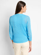 Bright blue lightweight cardigan on a woman from the back, showing fine knit, 3/4 sleeves, and ribbed hem.