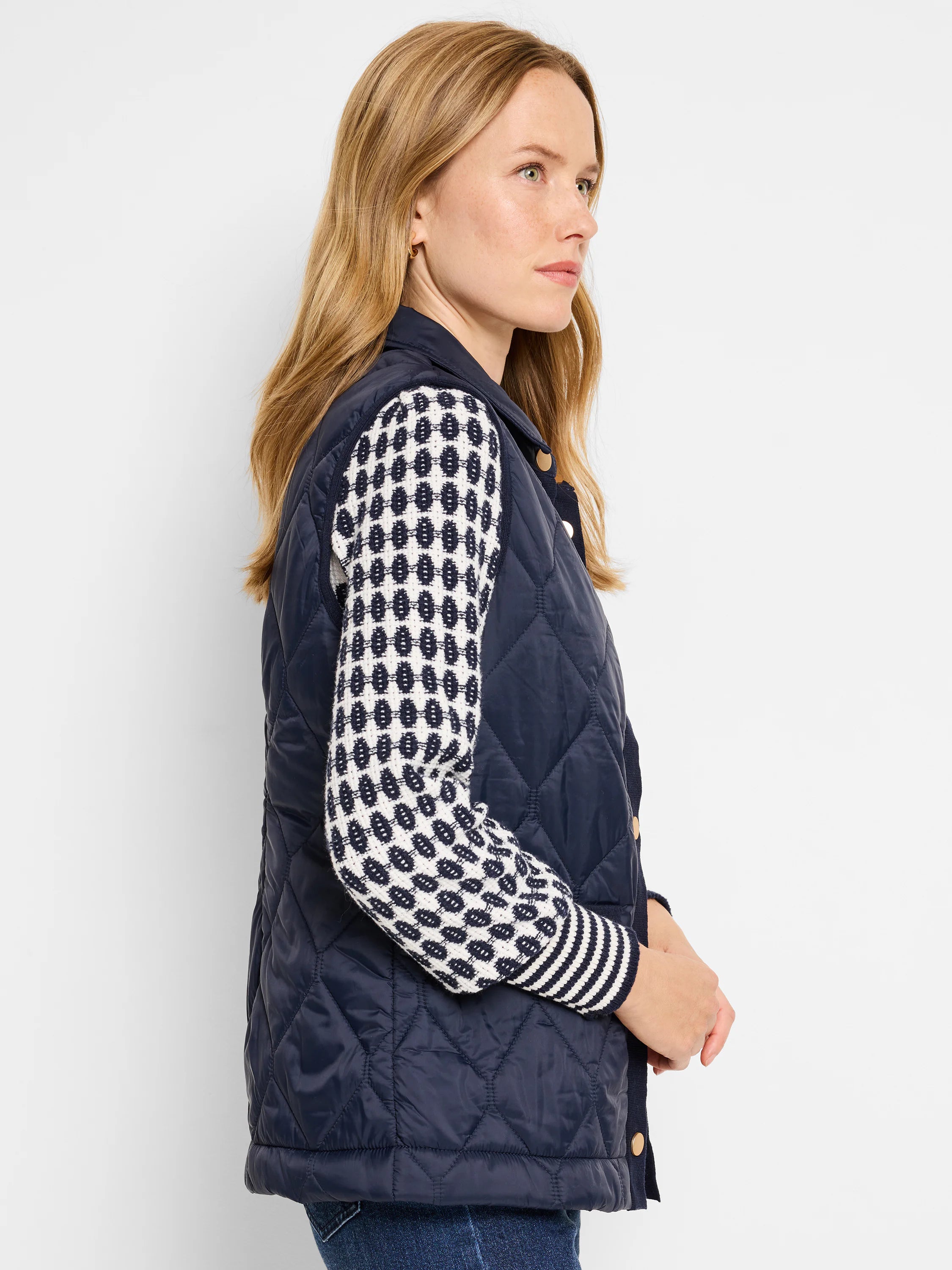 Navy blue quilted puffer vest.  Diamond quilting pattern.  Features a contrasting cream and navy knit trim. Gold buttons.