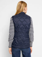 Navy blue quilted puffer vest. Diamond quilting pattern.  Shown with a cream and navy patterned sweater.
