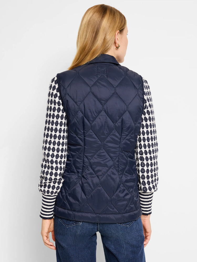 Navy blue quilted puffer vest. Diamond quilting pattern.  Shown with a cream and navy patterned sweater.