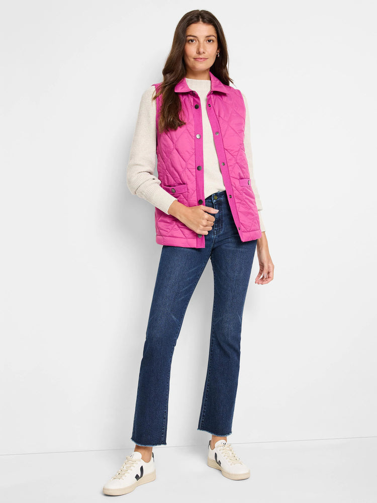 Pink quilted puffer vest with snap closures and pockets.  Shown on a model with a cream sweater and dark wash jeans.