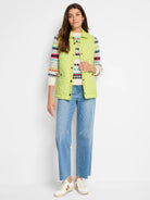 Lime green quilted puffer vest with gold buttons.  Model wears it over a multicolored striped sweater.