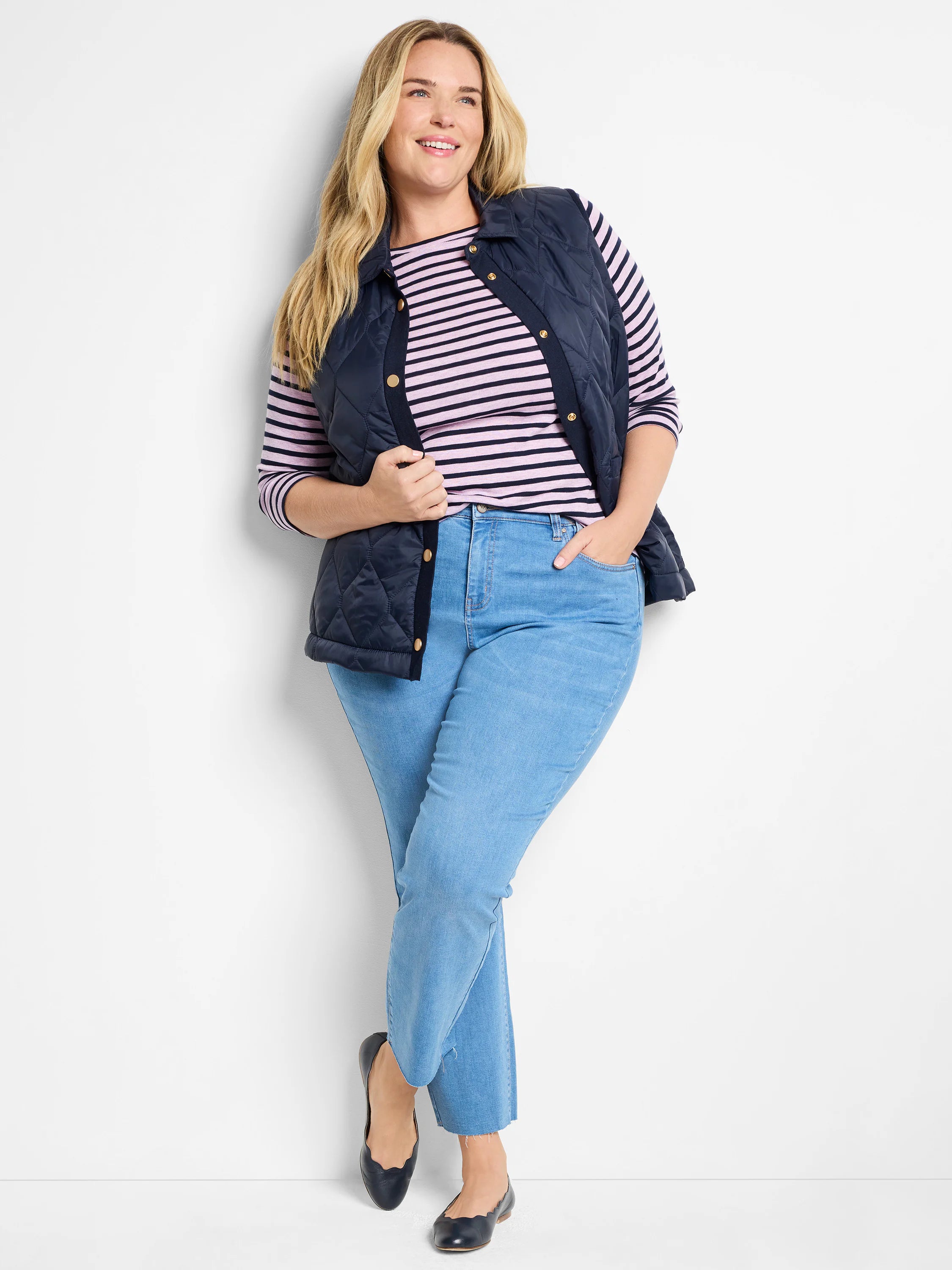 Navy blue quilted puffer vest with gold buttons.  Model wears it over a pink and white striped shirt.