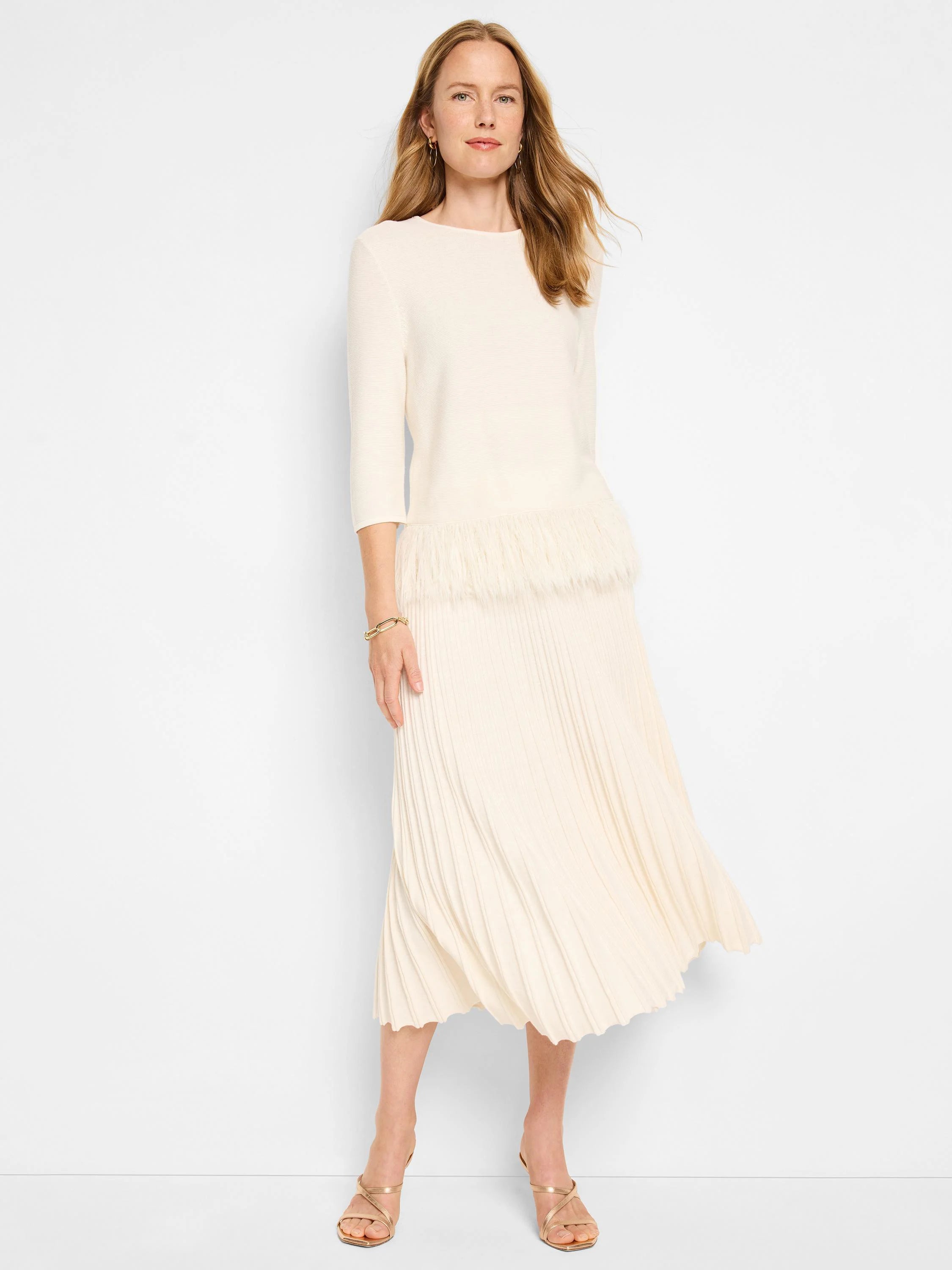 Off-white sweater with a feather fringe hem, paired with a pleated off-white midi skirt.