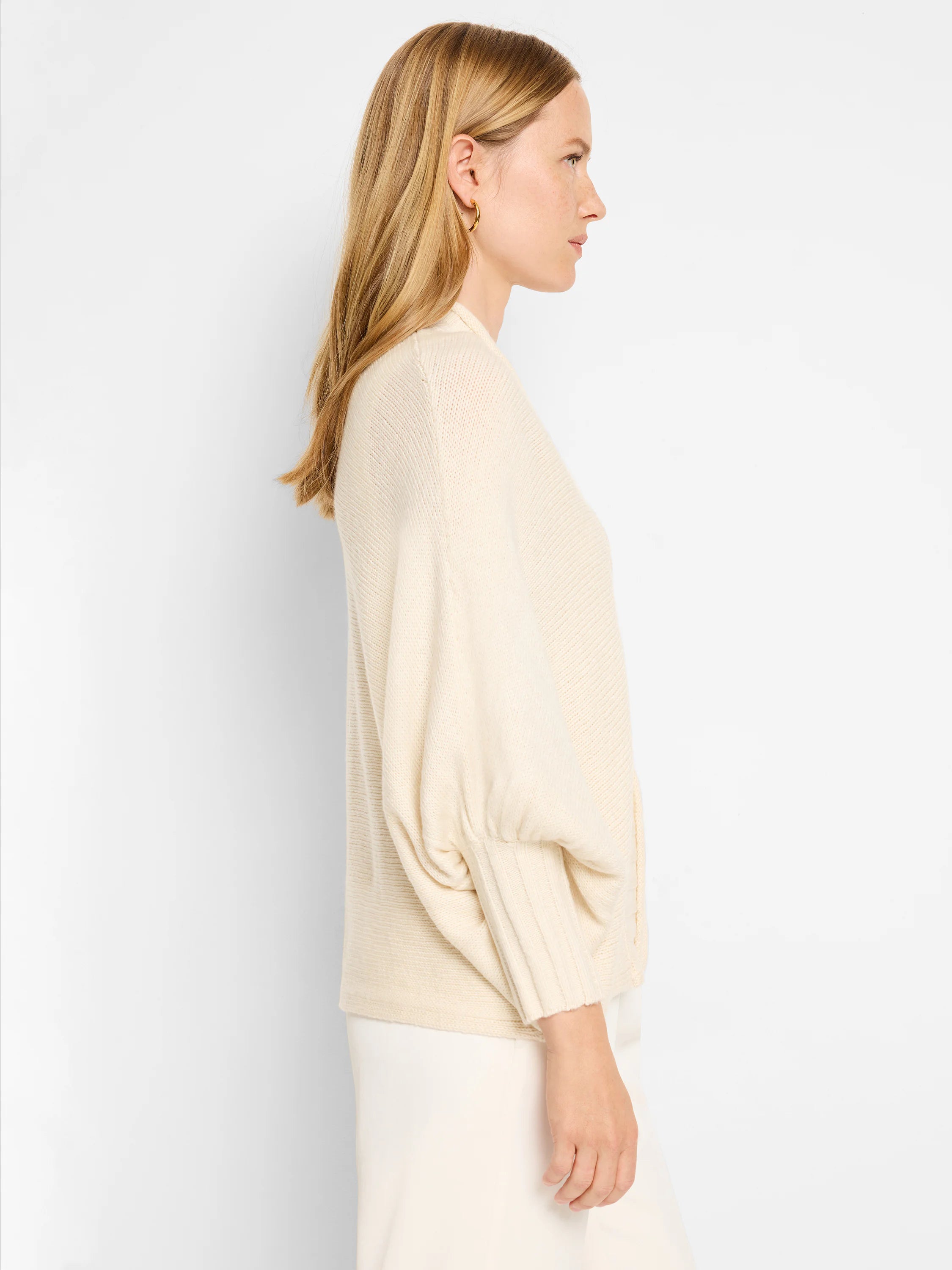 Off-white, knitted cardigan.  Puff sleeves, ribbed cuffs and hem.  Side profile view.