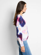 White sweater with blurred pink, purple, and blue tie-dye pattern.  Long sleeves, ribbed cuffs and hem.