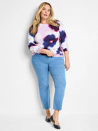 Cream-colored sweater with blurry purple, pink, and blue floral pattern.  Three-quarter sleeves.