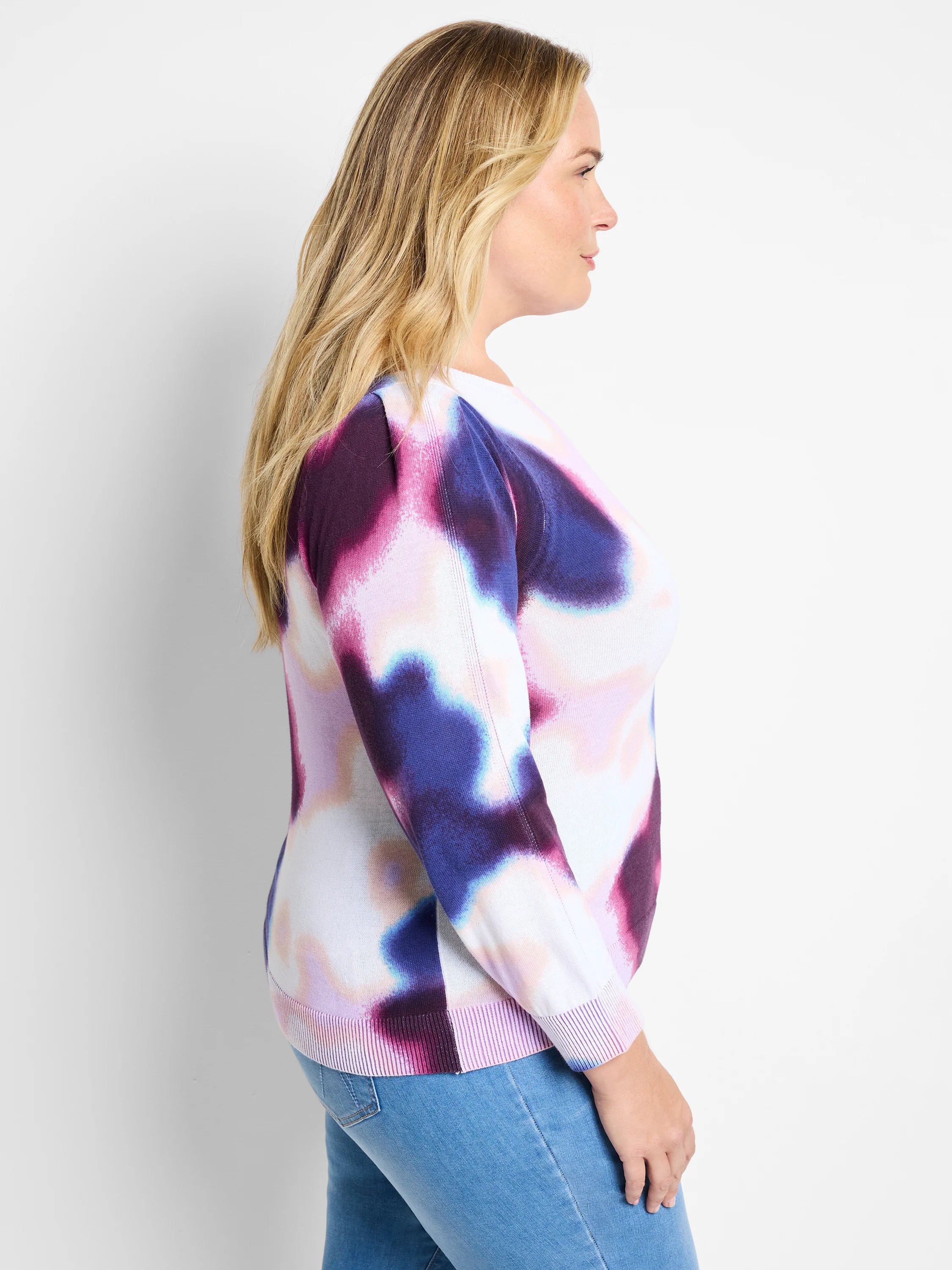 White sweater with purple, pink, and blue abstract print. Long sleeves, ribbed cuffs and hem.