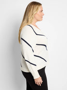 Cream-colored cardigan with diagonal navy stripes, long sleeves.