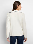 Off-white sweater with dark navy blanket stitch trim on collar and cuffs.  Long sleeves.
