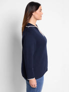 Navy blue sweater with off-white blanket stitch trim at collar and cuffs.  Ribbed knit texture.
