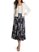 Off-white ribbed cardigan with dark trim, shown with a navy and beige abstract print midi skirt.