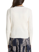 Off-white ribbed cardigan with a dark navy trim at the neckline.  Long sleeves.