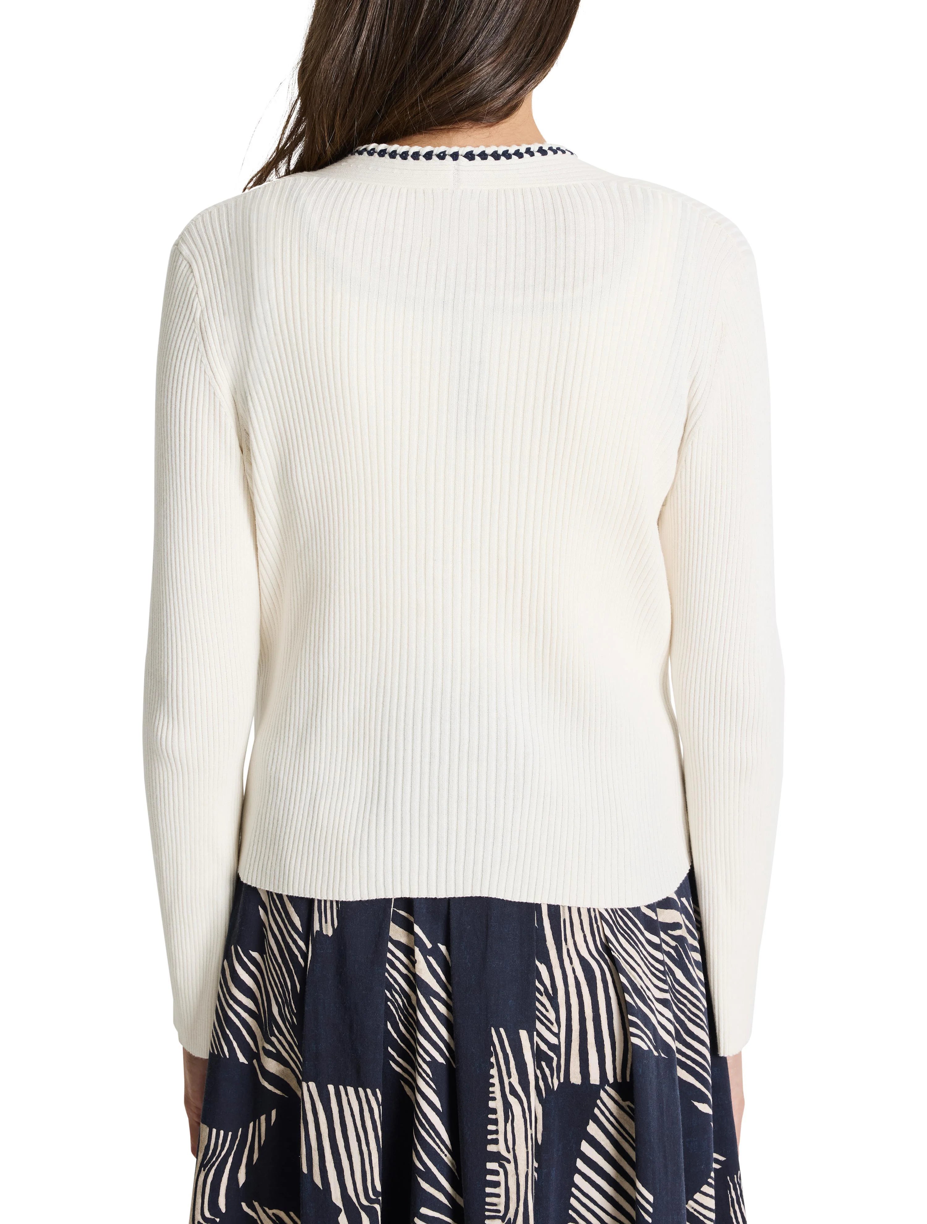 Off-white ribbed cardigan with a dark navy trim at the neckline.  Long sleeves.