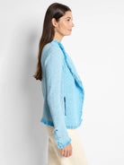Light blue mix knit jacket with fringe along the open front, hem, and cuffs. Silver buttons detail the cuffs.