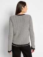 Off-white sweater jacket with black geometric pattern and frayed edges.  Black trim at neckline and cuffs.