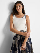 Off-white ribbed tank top with navy trim.  Neckline and hem feature a decorative dark blue edging.