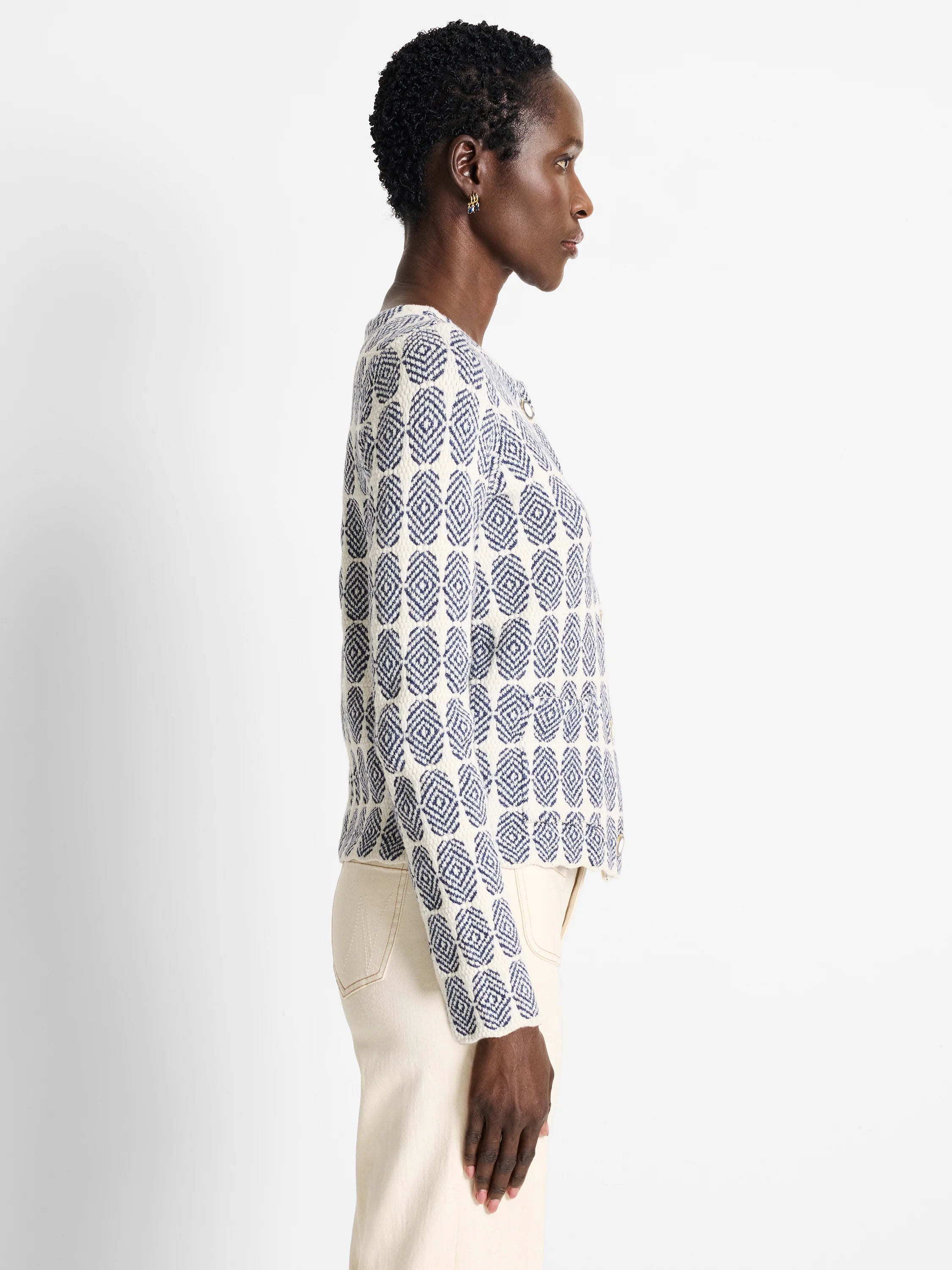 Off-white knit jacket with a navy blue geometric pattern.  The jacket is buttoned and has a cropped length.