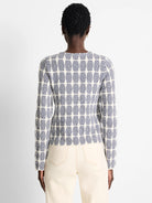 Off-white knit jacket with a navy blue geometric pattern.  Long sleeves. Rear view.