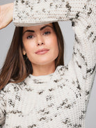Cream-colored knit sweater with dark gray/black flecks.  Long sleeves, crew neck.