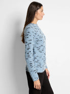 Light blue sweater with dark gray speckled pattern, long sleeves, crew neck.