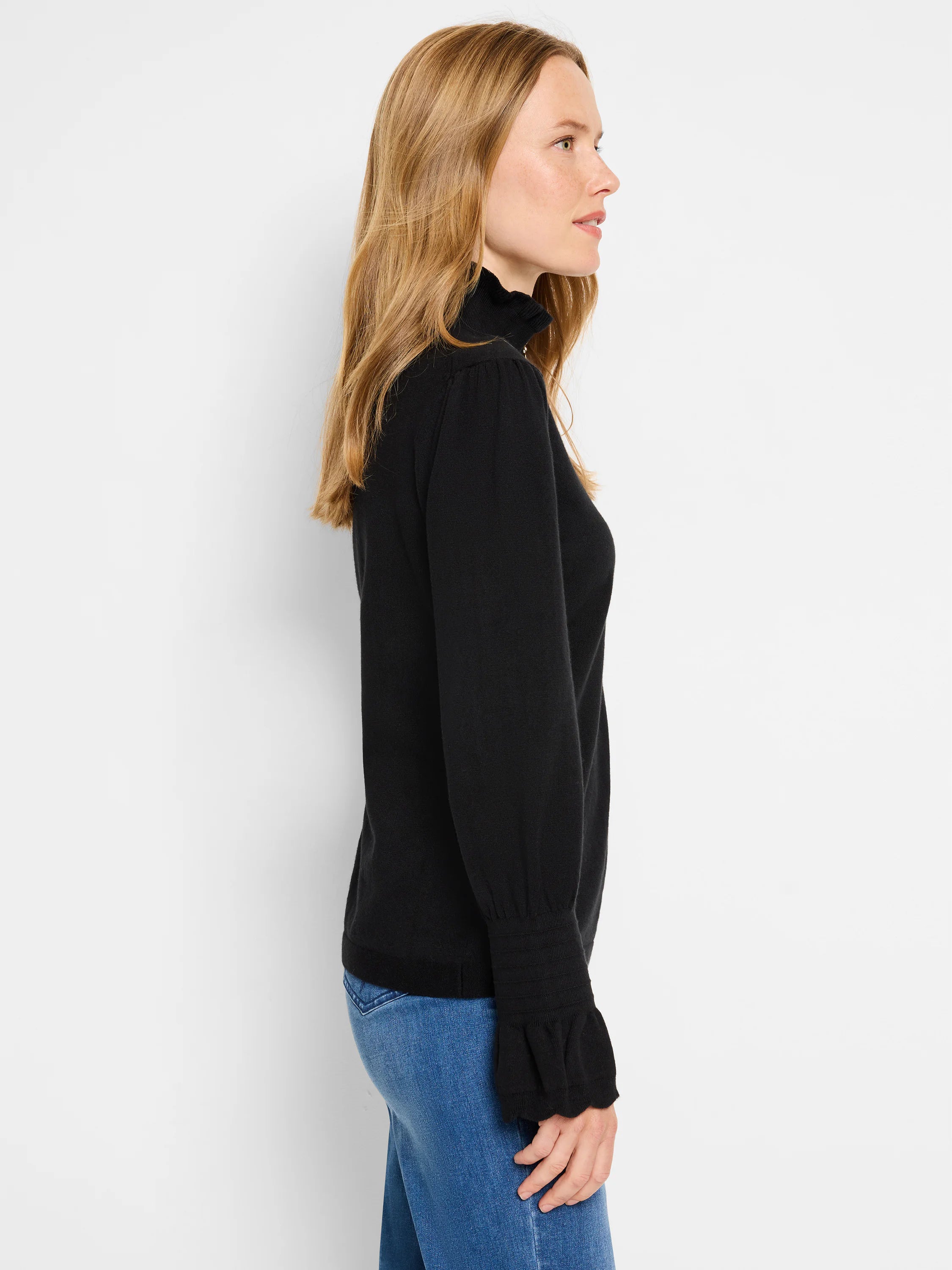 Black long-sleeve sweater with ruffled collar and cuffs.  Side profile view.