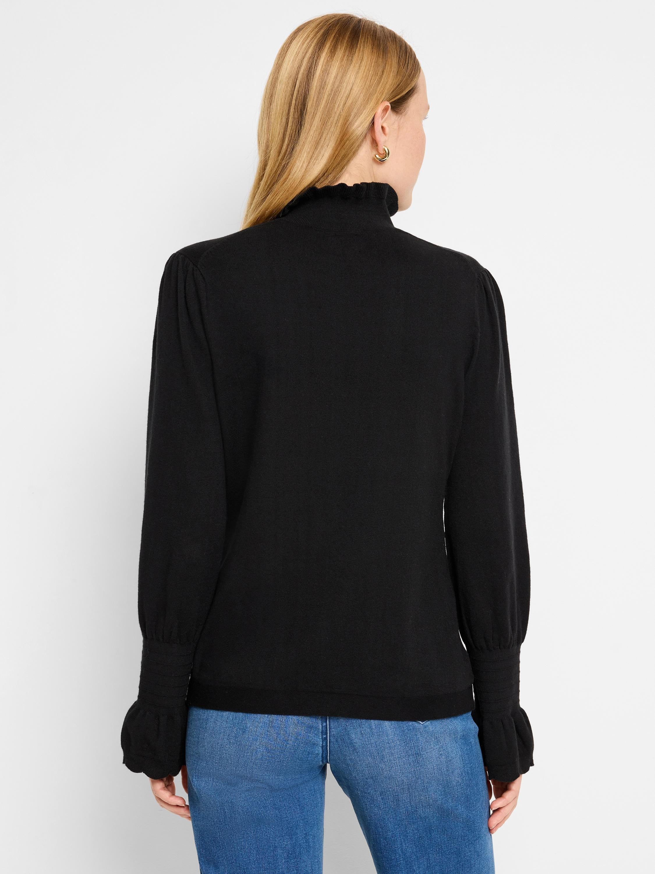 Black mock-neck sweater, long sleeves with ruffled cuffs, and slightly puffed shoulders.