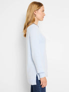 Light blue cotton cashmere sweater.  Features long sleeves, side slits, and a small black and white patterned neckline.