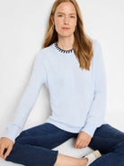 Light blue long-sleeved sweater with dark navy trim around the neckline.