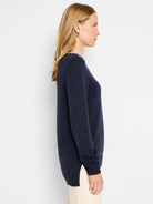Dark navy blue long-sleeved sweater.  Small off-white detail at neckline. Side slits. Knit texture.