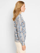 Off-white sweater with blue and brown speckled pattern; henley neckline; long sleeves.
