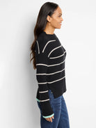 Black waffle-knit sweater with thin off-white stripes and light teal cuffs.