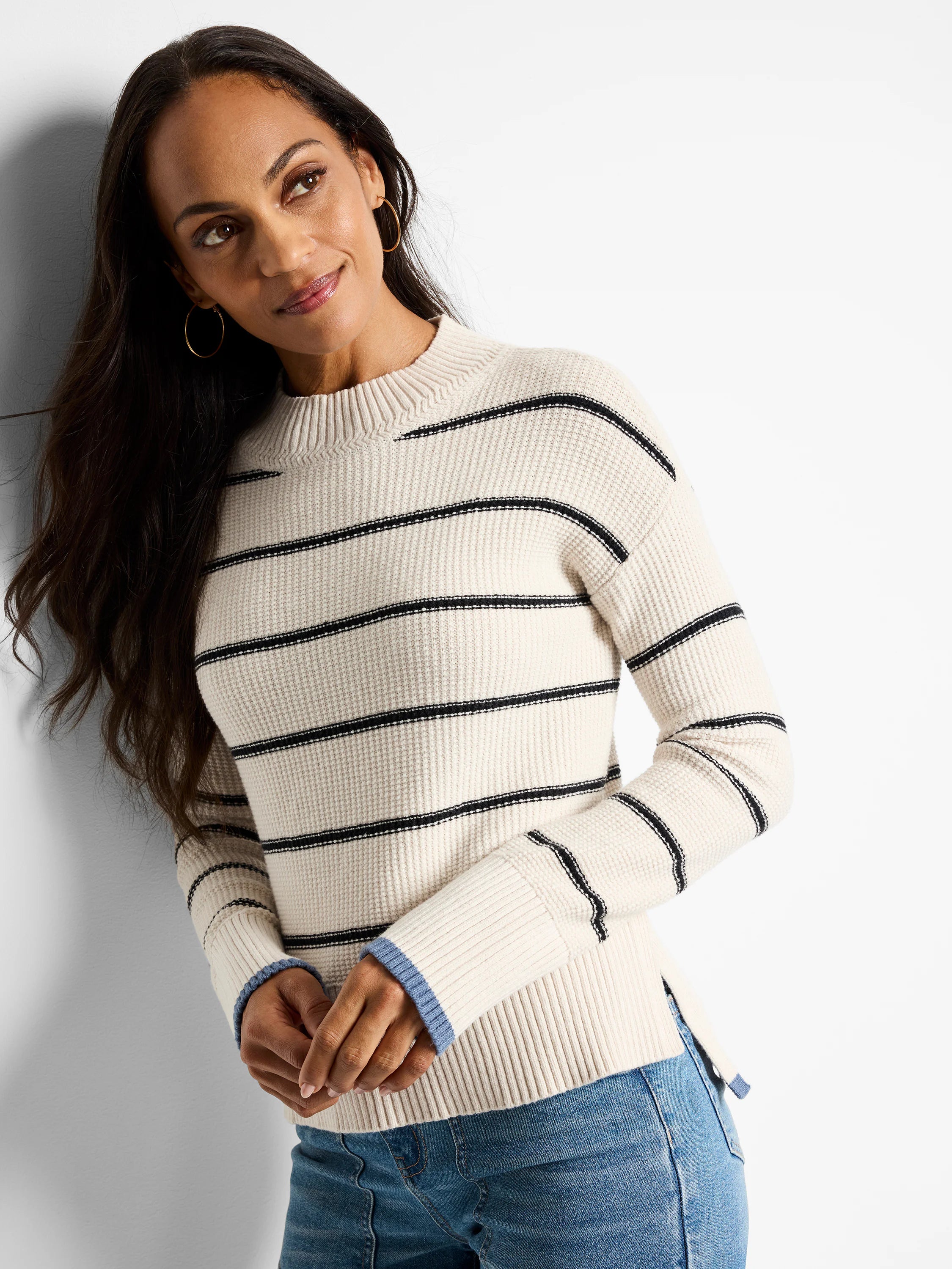 Off-white waffle-knit sweater with thin black horizontal stripes and light blue inner cuffs. Mock neck.
