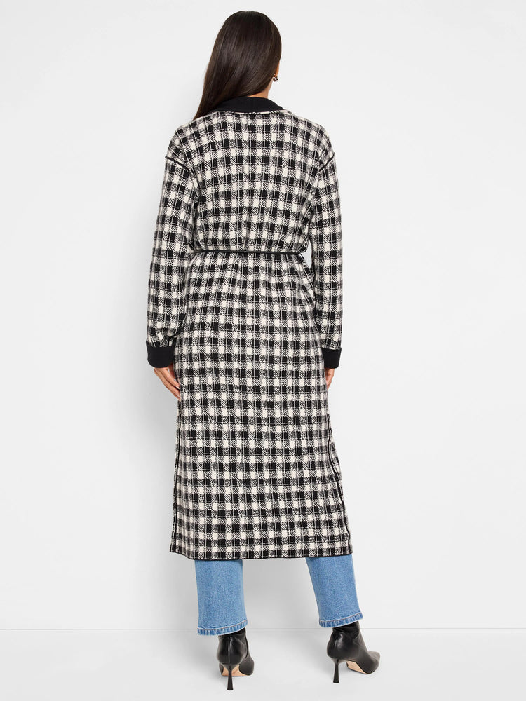 Black and off-white houndstooth long jacket with a self-tie belt; long sleeves and side slits.