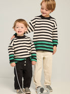 Cream and black horizontal striped waffle-knit sweater. Green stripes at cuffs and hem.