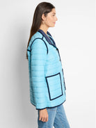 Light blue quilted puffer jacket with navy trim, snap buttons, and front patch pockets.