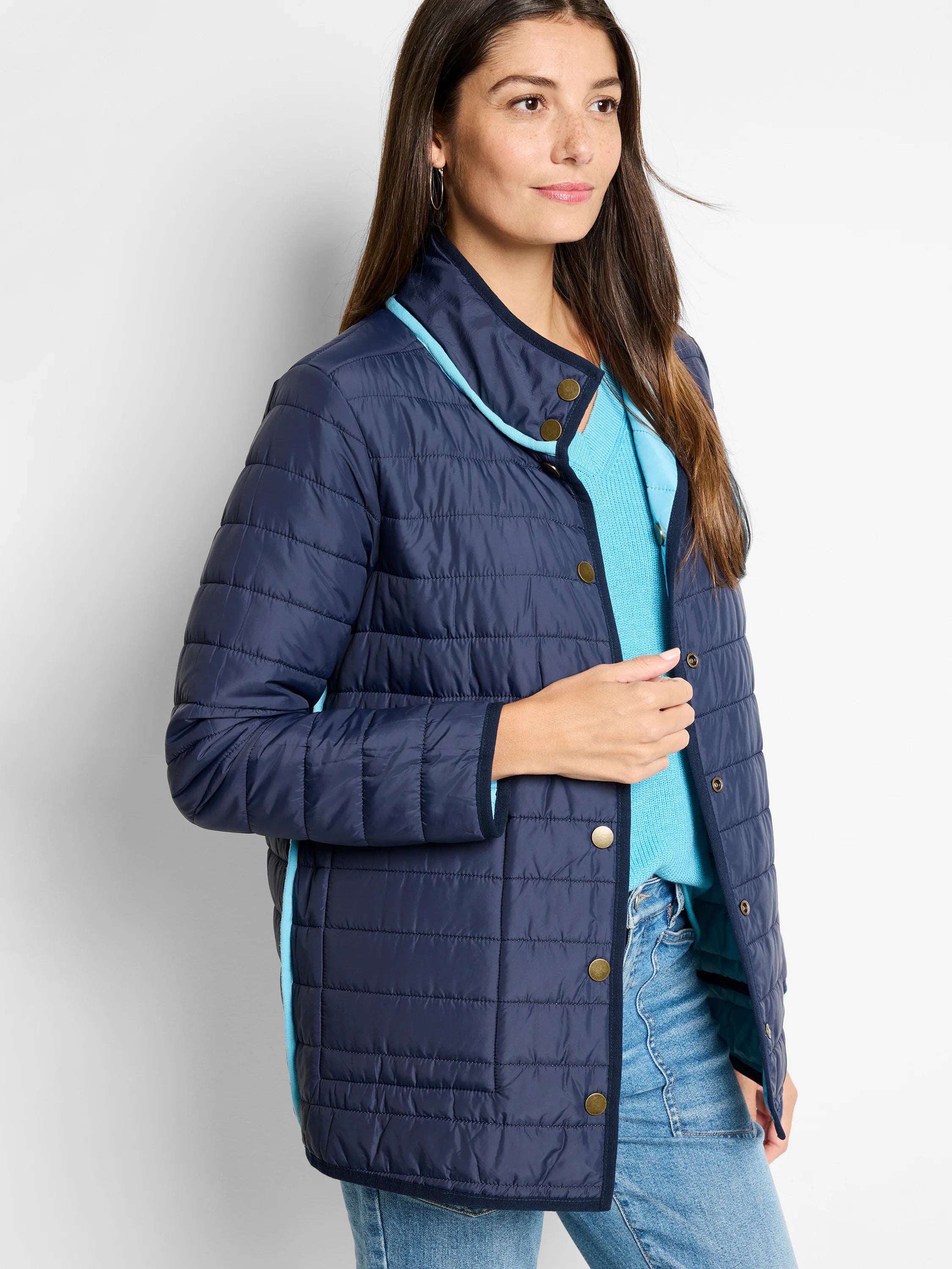 Navy quilted reversible puffer jacket with light blue trim and gold snap buttons.