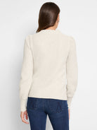 Cream waffle stitch sweater, mock neck, long sleeves with slight puff shoulders. Shown from the back.