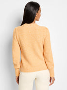 Peach waffle stitch sweater with ribbed mock neck, puff sleeves, and ribbed cuffs. Back view on model.