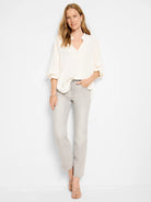 Off-white, loose-fitting blouse; light gray, straight-leg jeans with frayed hems; model shown for scale.