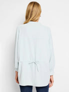 Light blue collared shirt with long sleeves and a drawstring waist.  Back view.