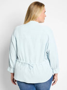 Light blue, long-sleeve blouse with cinched waist and slight puff sleeves.  Back view.