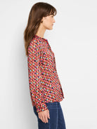 Long-sleeve button-up blouse. Pink, orange, brown, and gray abstract pattern on dark background.
