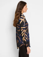 Long-sleeved shirt; navy, brown, and beige abstract leaf print on black background.  Collared.